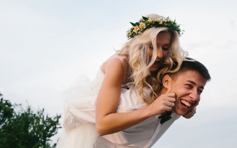 groom carries his bride on his back outdoors