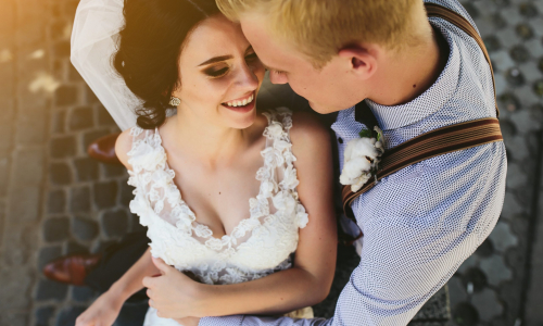 Bride and groom sit on the bench and having fun
